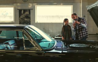 dad teaching young daughter about cars while in the garage