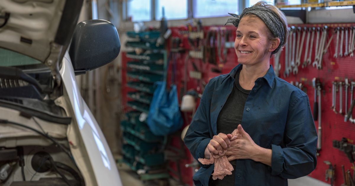 Female automotive technician in a shop smiling