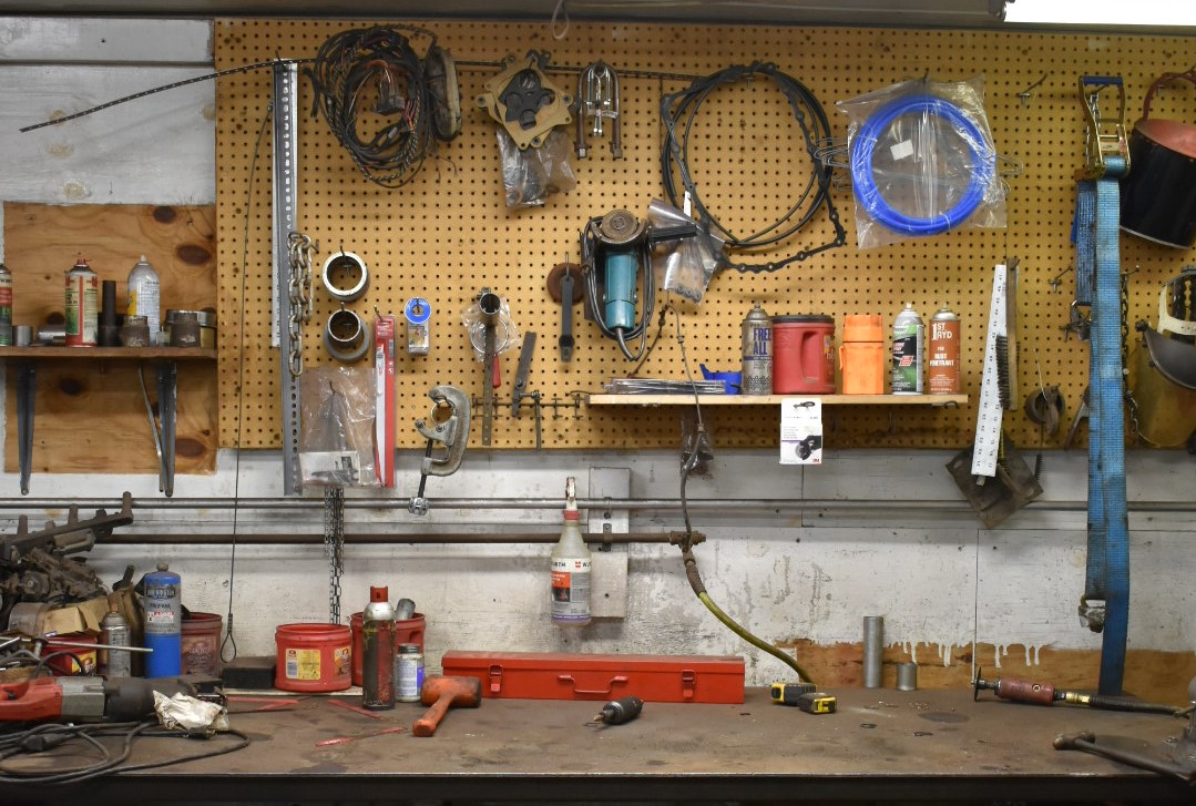 A wall of an automotive repair shop with different tools and equipment hanging up