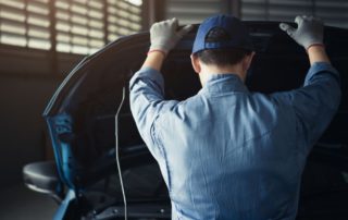 mechanic looking under the hood of a car