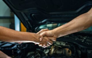 Mechanics shaking hands in an auto shop